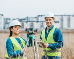 Smiling,surveyors,with,digital,level,and,tablet,looking,at,camera